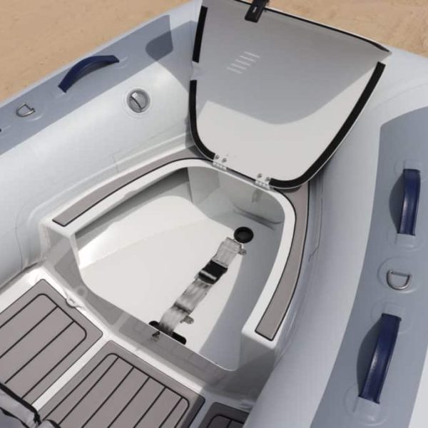 Interior de un bote inflable con un compartimento de almacenamiento, detalles en azul y superficie de piso gris. Ideal para actividades náuticas y recreativas.