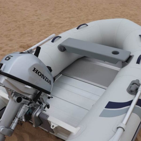 Bote inflable Highfield con motor Honda en una playa de arena. El bote presenta un diseño cómodo y funcional, ideal para actividades acuáticas y navegación.