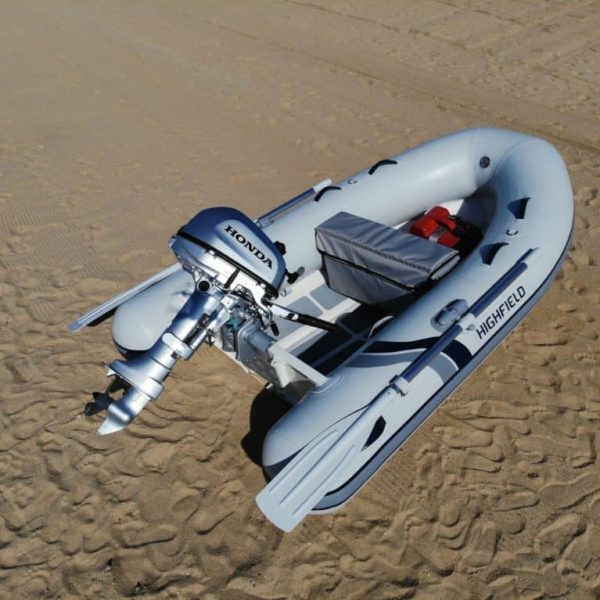 Bote inflable Highfield con motor Honda, estacionado en la arena, ideal para actividades acuáticas y exploración.