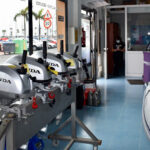 Tienda de motores fuera de borda Honda, con varios motores expuestos en un soporte, vista interior que muestra un ambiente de venta y mantenimiento náutico.
